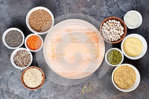 Superfoods and cereals selection in bowls with wooden board for your text on grey concrete background