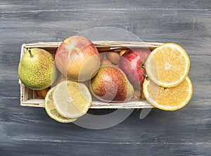 Superfoods and health detox diet food concept variety of fruits in a wooden box kumquat, oranges, pear, lemon, top view