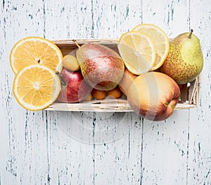 Superfoods and health or detox diet food concept variety of fruits in a wooden box kumquat, oranges, pear, lemon, top view