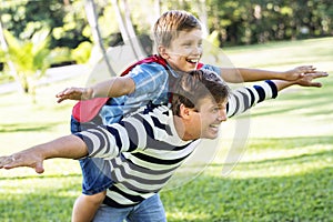 Superhero boy flying on the back of his dad