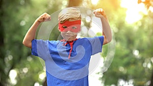 Superhero boy showing muscles, game as psychotherapy for child confidence photo