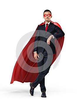 A superhero in a business suit and a red cape leaning on an invisible object on white background.