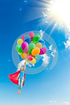 Superhero child playing with bright multicolor balloons