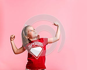 Superhero kid against blue pink background. Girl power concept. Confident child shows muscles. Kindergarten kid ready to