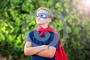 Superhero kid against green background outdoor. Childhood, success and and power concept