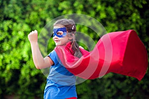 Superhero kid against green background outdoor. Childhood, success and and power concept