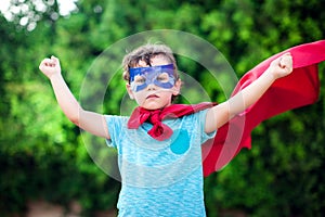 Superhero kid against green background outdoor. Childhood, success and and power concept