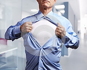 Superhero. Mature businessman tearing his shirt off in office