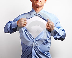 Superhero. Mature businessman tearing his shirt off over white b