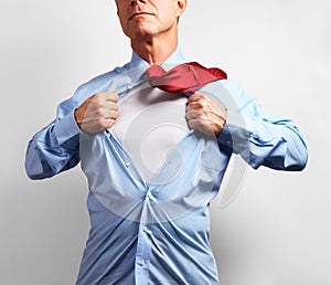 Superhero. Mature businessman tearing his shirt off over white b