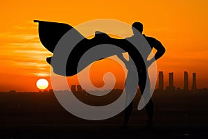 Superhero silhouette back view over watch the city at sunset or sunrise