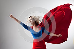 Superhero Woman. Young and beautiful blonde in image of superheroine in red Cape growing