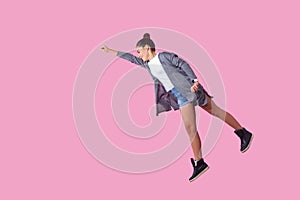 Superman. Portrait of cheerful ambitious brunette teenage girl flying with one raised hand, feeling super power. pink background