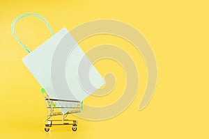 supermarket background, online shopping, gift bag in supermarket trolley on yellow