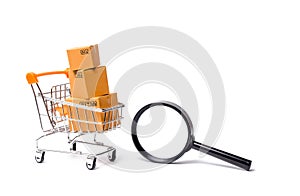 Supermarket cart with boxes, merchandise and magnifying glass: the concept of buying and selling goods and services,