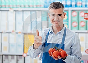 Supermarket clerk holding tomatoes