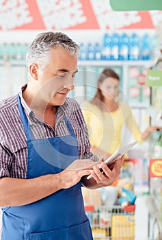 Supermarket clerk using a tablet photo