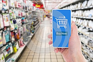 In the supermarket, close-up of a man`s hand holding a mobile phone to shop online.