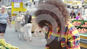 Supermarket employee african american woman with an afro hairstyle sorts the fruit close up