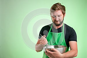 Supermarket employee with green apron and black t-shirt hold metal bowl and wire in his hand