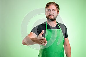Supermarket employee with green apron and black t-shirt shaking hand