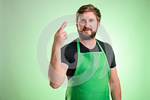 Supermarket employee with green apron and black t-shirt showing good luck