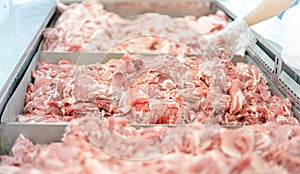 The supermarket employee preparing the Fresh pork meat slice on display tray for consumers select in a supermarket
