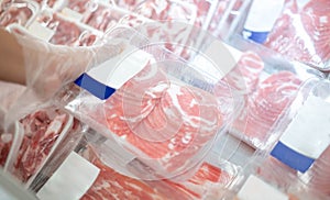 The supermarket employee preparing the Fresh pork meat slice on display tray for consumers select in a supermarket