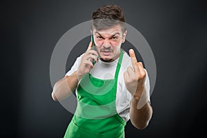 Supermarket employer talking at phone showing obscene gesture