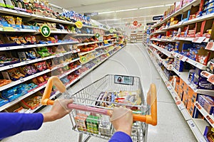 Supermarket Grocery Aisle with a Trolley and Full Shelves of Products