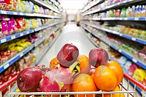 Supermarket interior, filled with fruit of shopping cart.