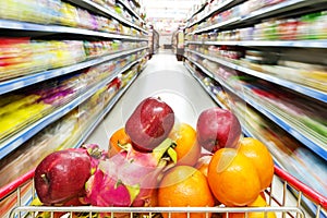 Supermarket interior, filled with fruit of shopping cart.