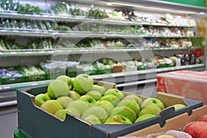 Supermarket interior with product shelves and fruits in boxes