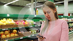 A supermarket and a mobile phone. Young beautiful woman smiling using mobile phone while shopping in store