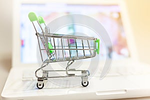 Supermarket shopping cart on laptop background close-up