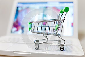 Supermarket shopping cart on laptop background close-up, macro, online shopping concept and purchasing power, consumer