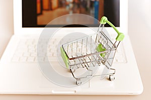 supermarket shopping cart on laptop background close-up, macro, online shopping concept and purchasing power, consumer shopping