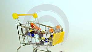 Supermarket trolley filled with medical capsules on a white background