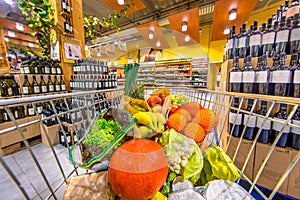 Supermarket trolley with fruit and vegetables on alcohol section