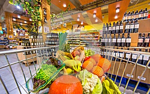 Supermarket trolley with fruit and vegetables on wine section