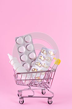 A supermarket trolley full of blister pills, a lot of pills in a wheelbarrow, nasal spray. Concept: home delivery of medicines.