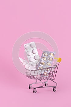 A supermarket trolley full of blister pills, a lot of pills in a wheelbarrow, nasal spray. Concept: home delivery of medicines.