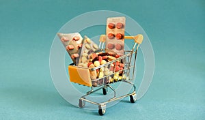 Supermarket trolleys filled with medical capsules on a coloured background