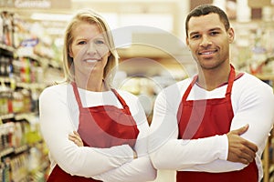 Supermarket Workers Standing In Grocery Aisle