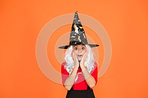Supernatural charmer gray hair. kid enchantress orange background. happy halloween. magic fantasy. scared small girl