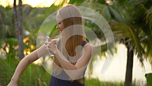 Superslowmotion shot of a beautiful young woman applying an antimosquito repellent spray on her skin. A tropical