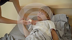 Superslowmotion shot of a sick little boy in a bed. Mother rubs boy`s chest with ointment with essential oils. Baby flu