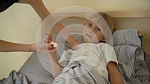 Superslowmotion shot of a sick little boy in a bed. Mother rubs boy`s chest with ointment with essential oils. Baby flu