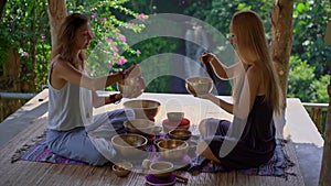 Superslowmotion shot of a woman master of Asian sacred medicine performs Tibetan bowls healing ritual for a client young