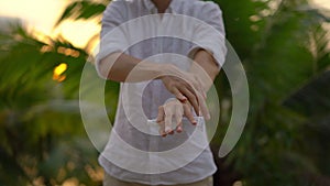 Superslowmotion shot of a young man applying an antimosquito repellent spray on his skin. A tropical background